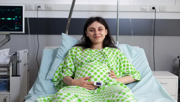Pregnant woman lying on a bed representing ovarian cancer surgery